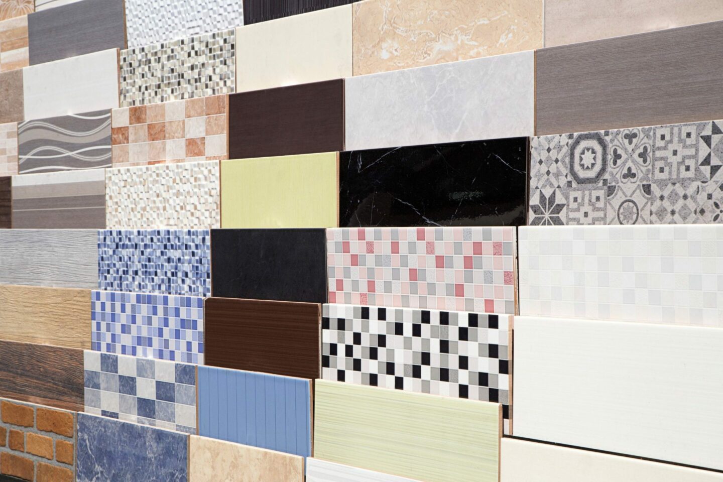 A selection of ceramic bathroom tiles of various colors, from dark, marble-like tile to a brightly-patterned