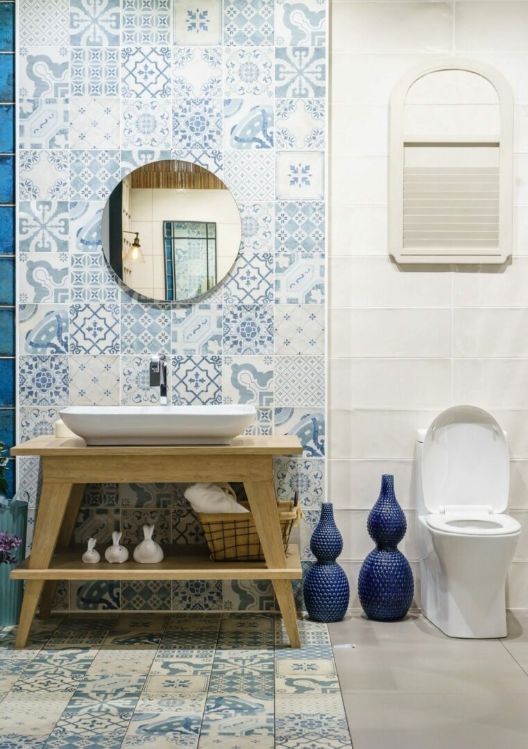 A charming small bathroom with white ceramic tiles and blue spanish tiles, with a freestanding sink and a round mirror.