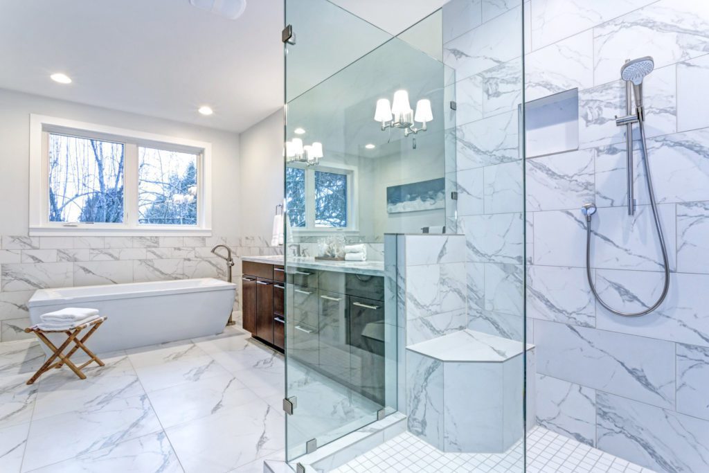 A bathroom with marble bathroom tiles in the shower, on the floor, and along the wall.