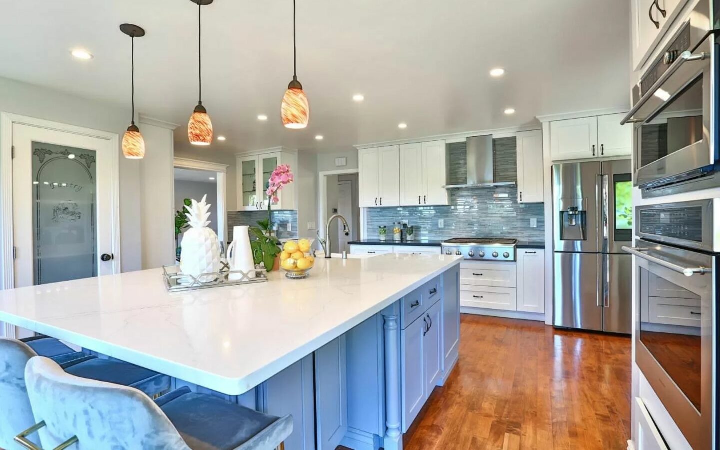Kitchen Remodeling - A newly-remodeled kitchen with a stainless steel sink and double-door refrigerator, rich mahogany-colored cabinets, granite countertops, and tile floors.