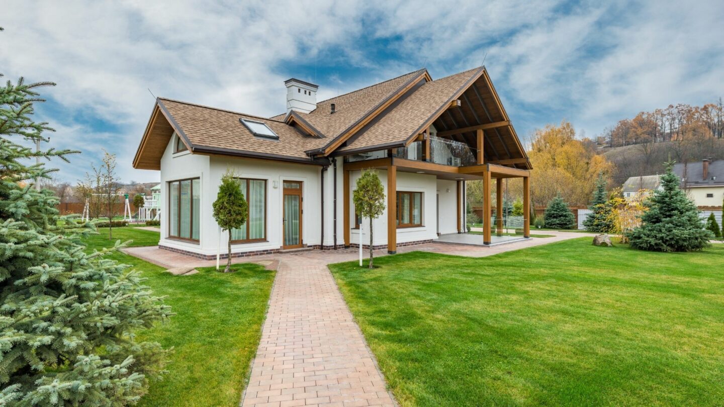 A custom home construction with white sidings and a brown roof in the midst of a bright green lawn