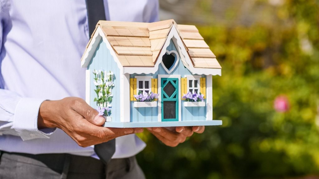 A homebuyer holds a small model of a custom home construction