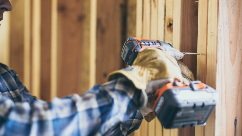 A homeowner who learned home remodeling tips drills into a wall. 